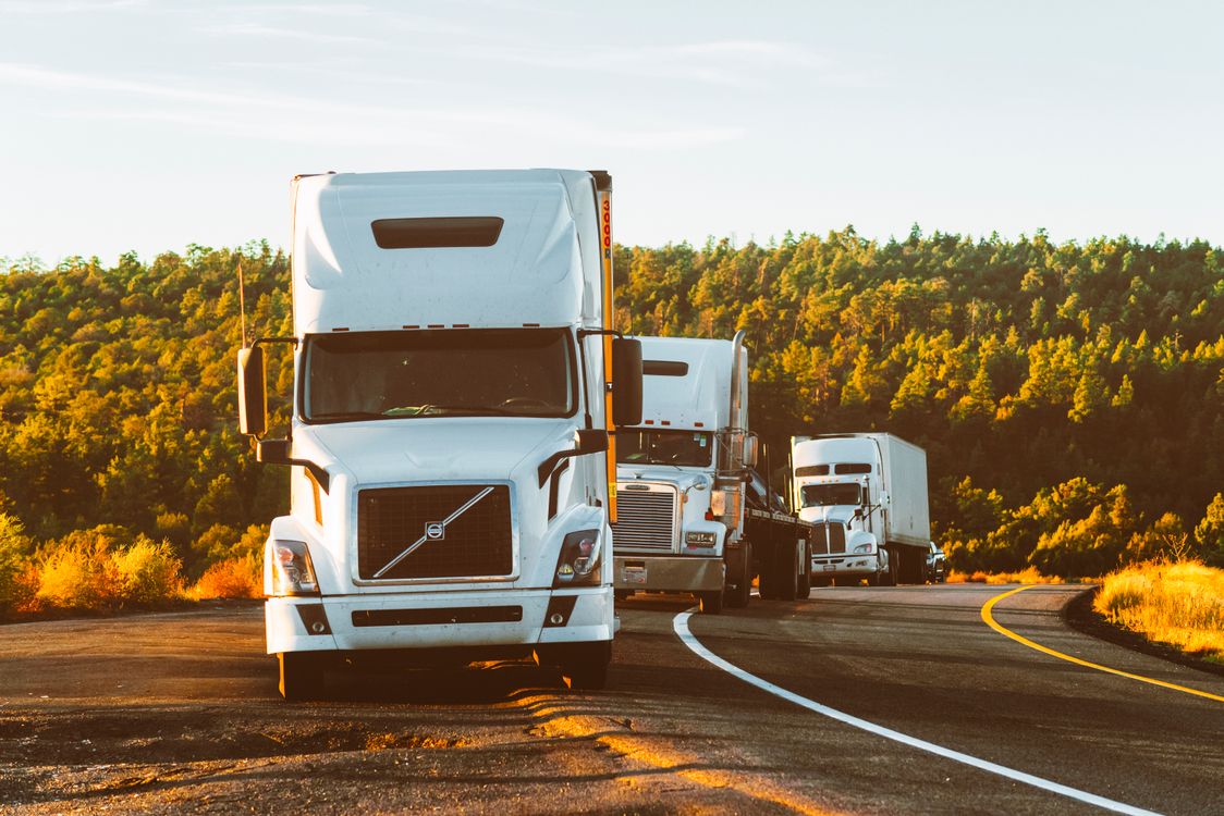 White semi-trucks traveling along a sunlit American highway